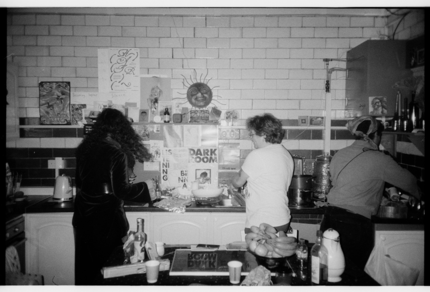The Listen Gallery kitchen with three people cooking the community meal for the 'Iraq: The Land of the Two Rivers' screening.